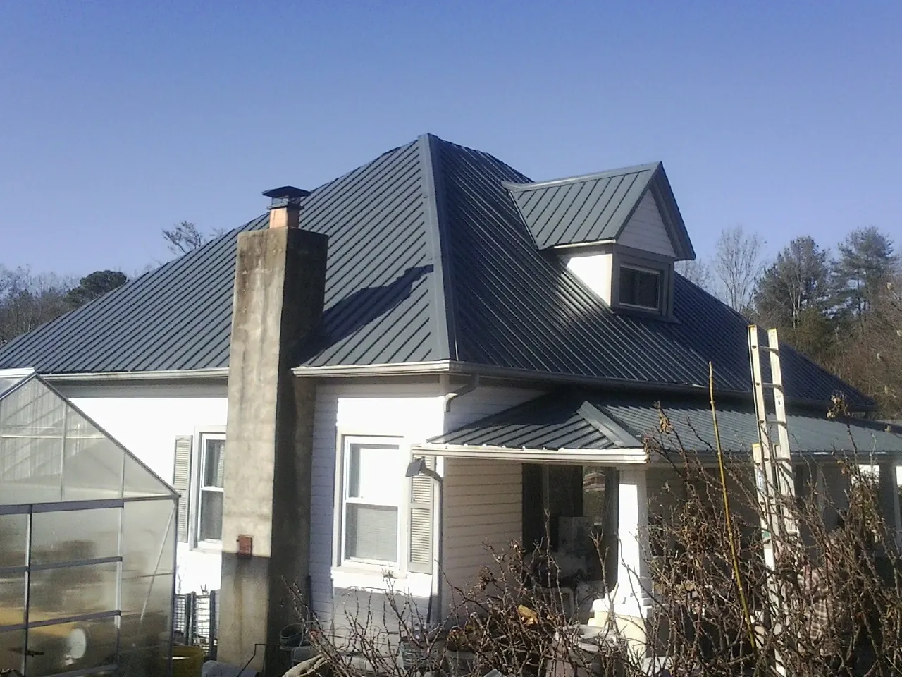 Dark blue standing seam metal roof on a white farmhouse with dormer — Slate & Tile Roof Repair by Roofing Brothers in Whitehouse