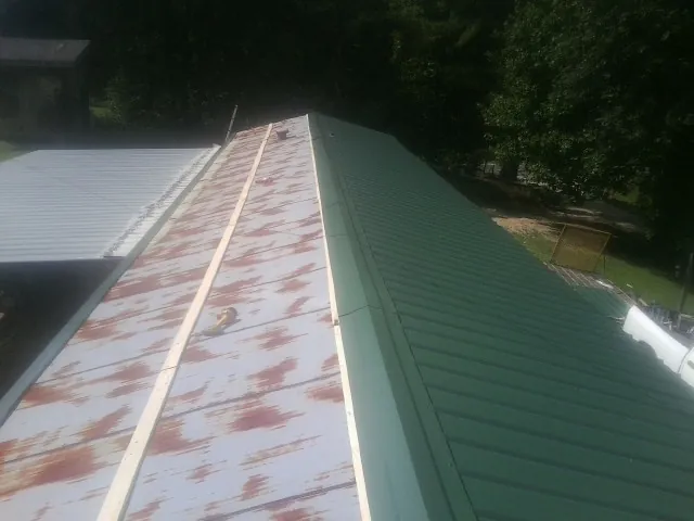 Old rusted panels beside newly installed green metal roofing — Wind Damage Roof Repair by Roofing Brothers in Whitehouse