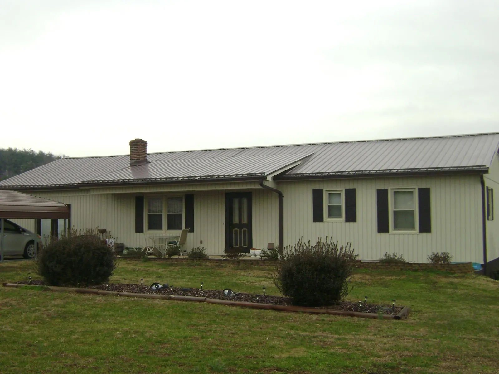 Brown metal roof on a cream sided ranch home with a brick chimney in Whitehouse