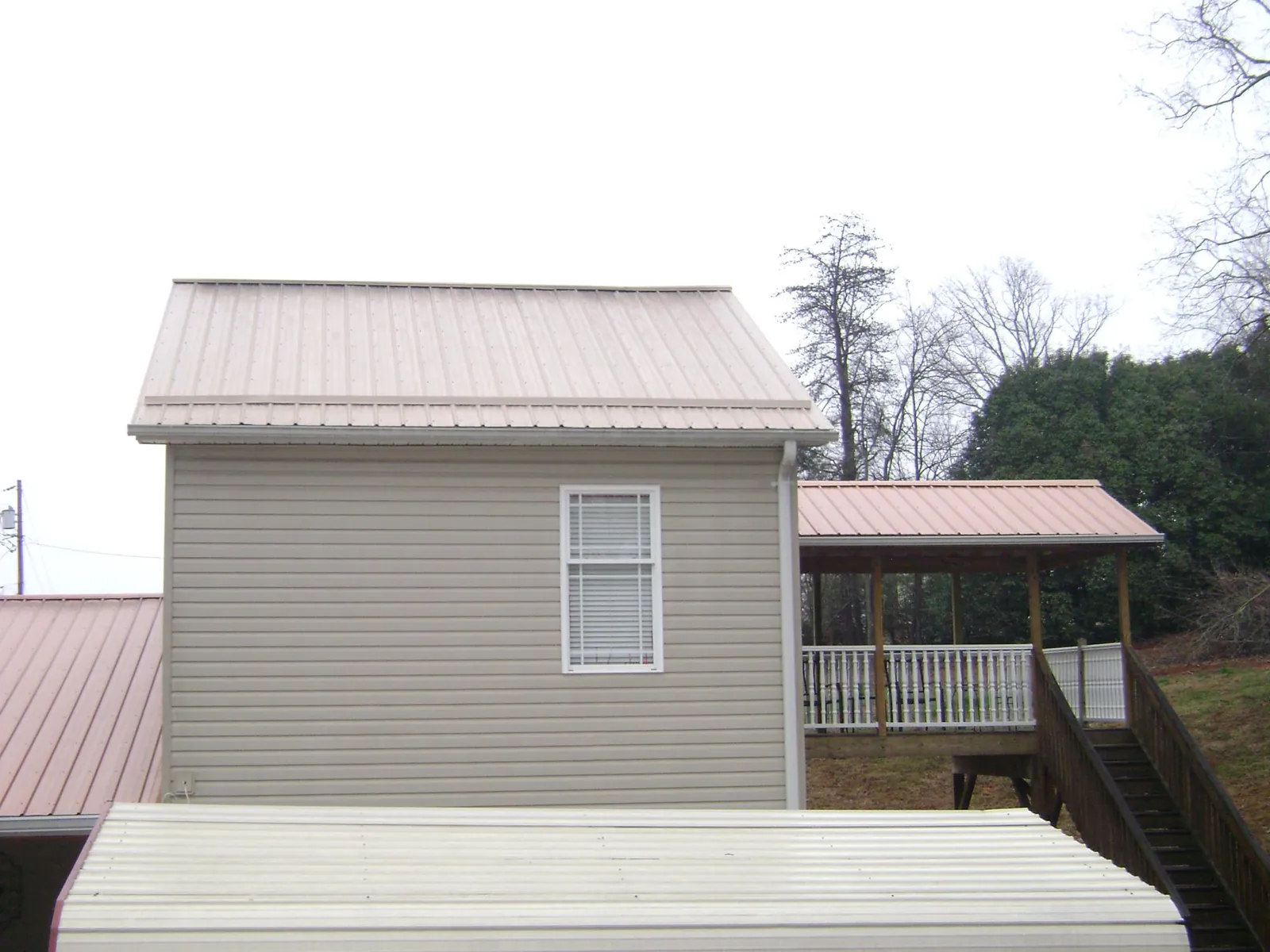 Tan metal roofs on a two story addition and attached porch, from a Roof Replacement job in Whitehouse